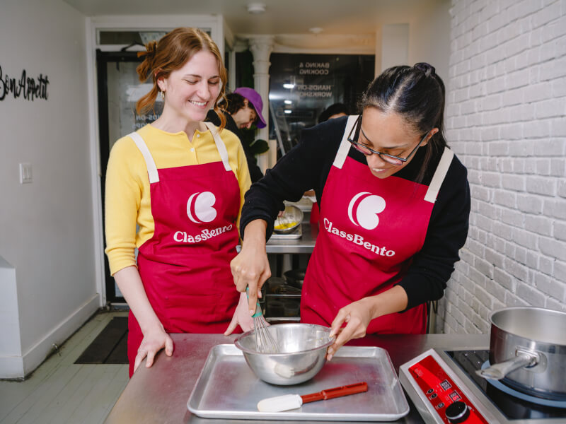 Two smiling women with a mixing bowl in a food class